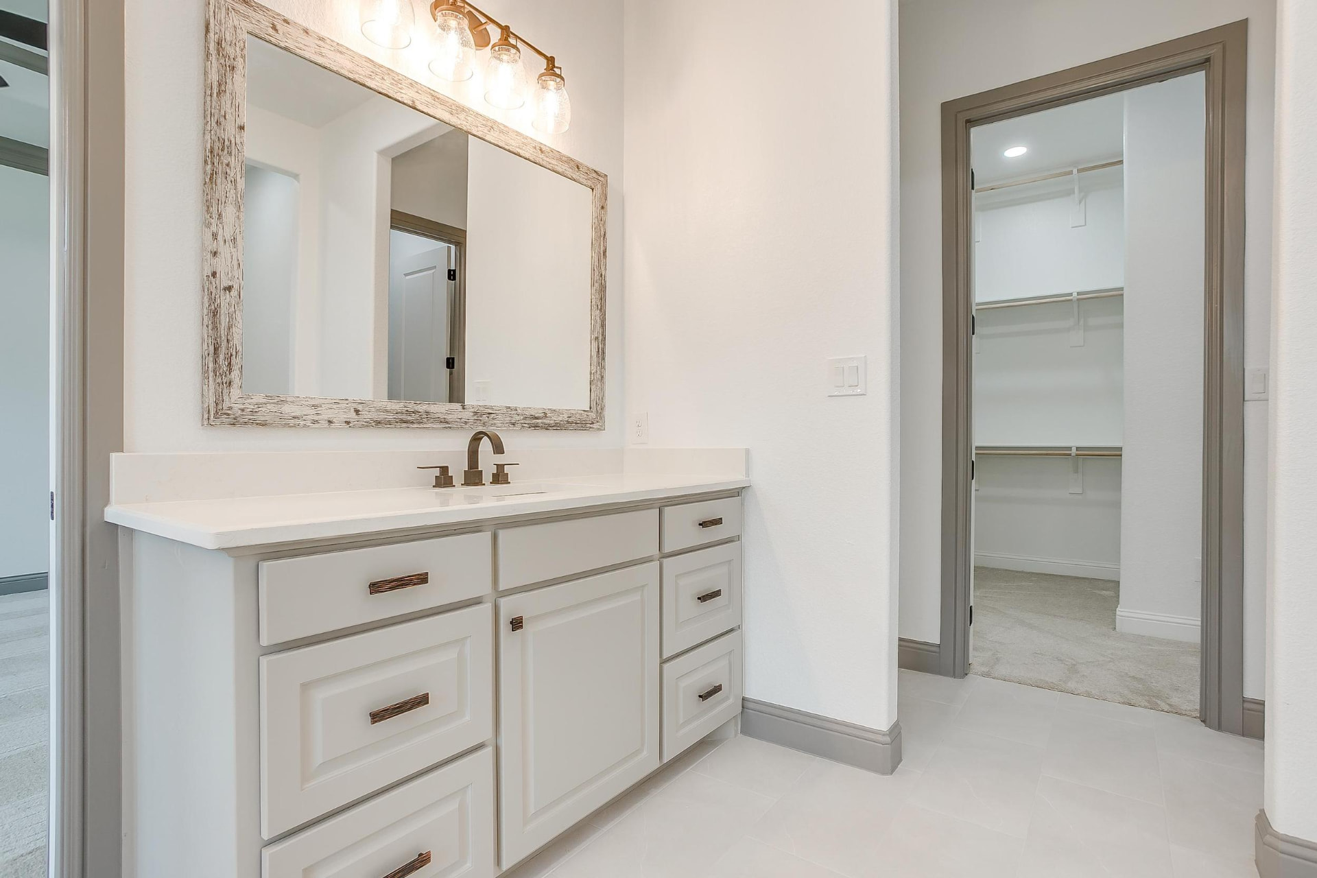 Primary vanity detail with bronze fixtures and sconce