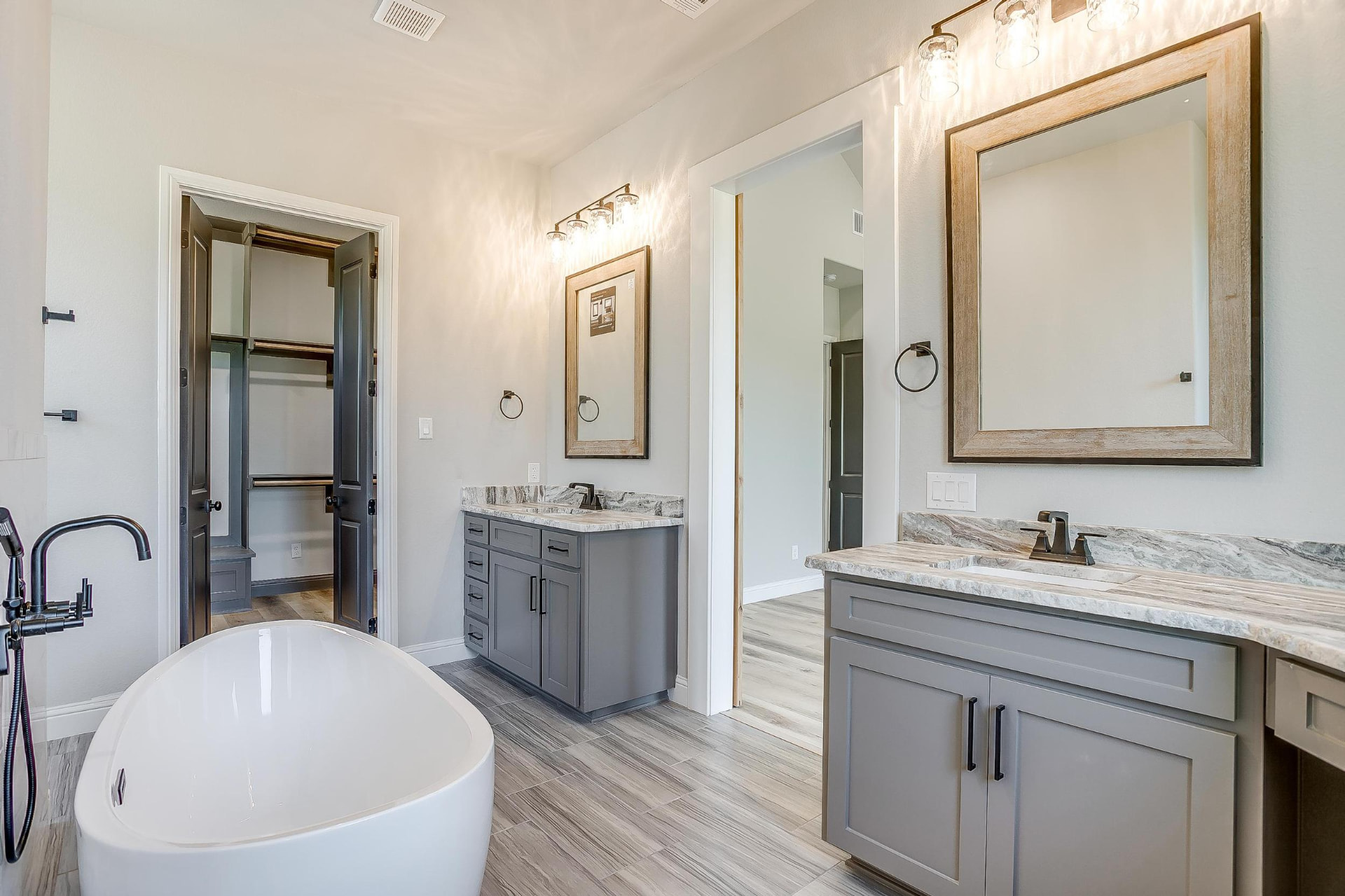 Primary bath with soaking tub, dual vanities, and walk-in closet