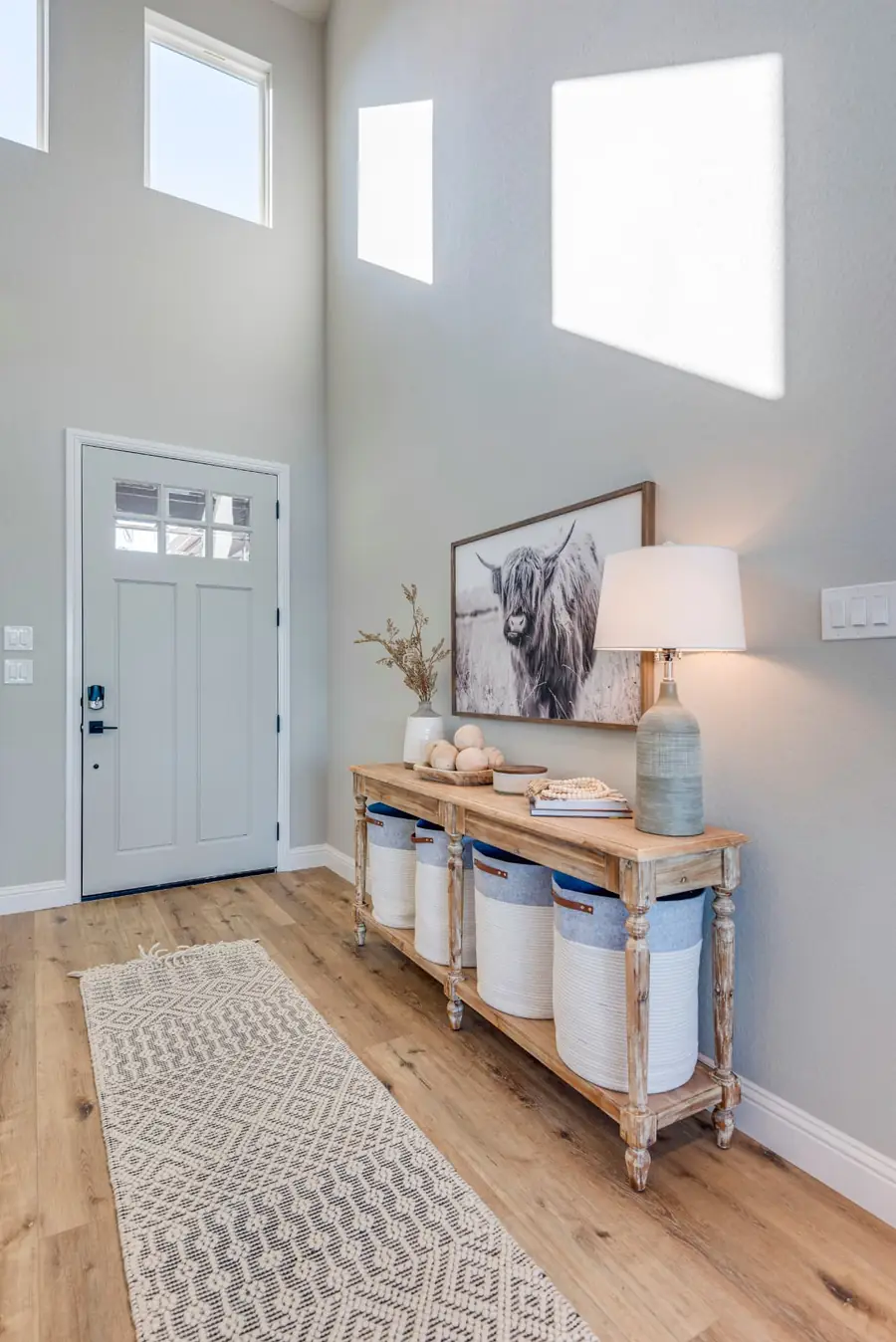 High-ceiling foyer with light wood console table and large artwork