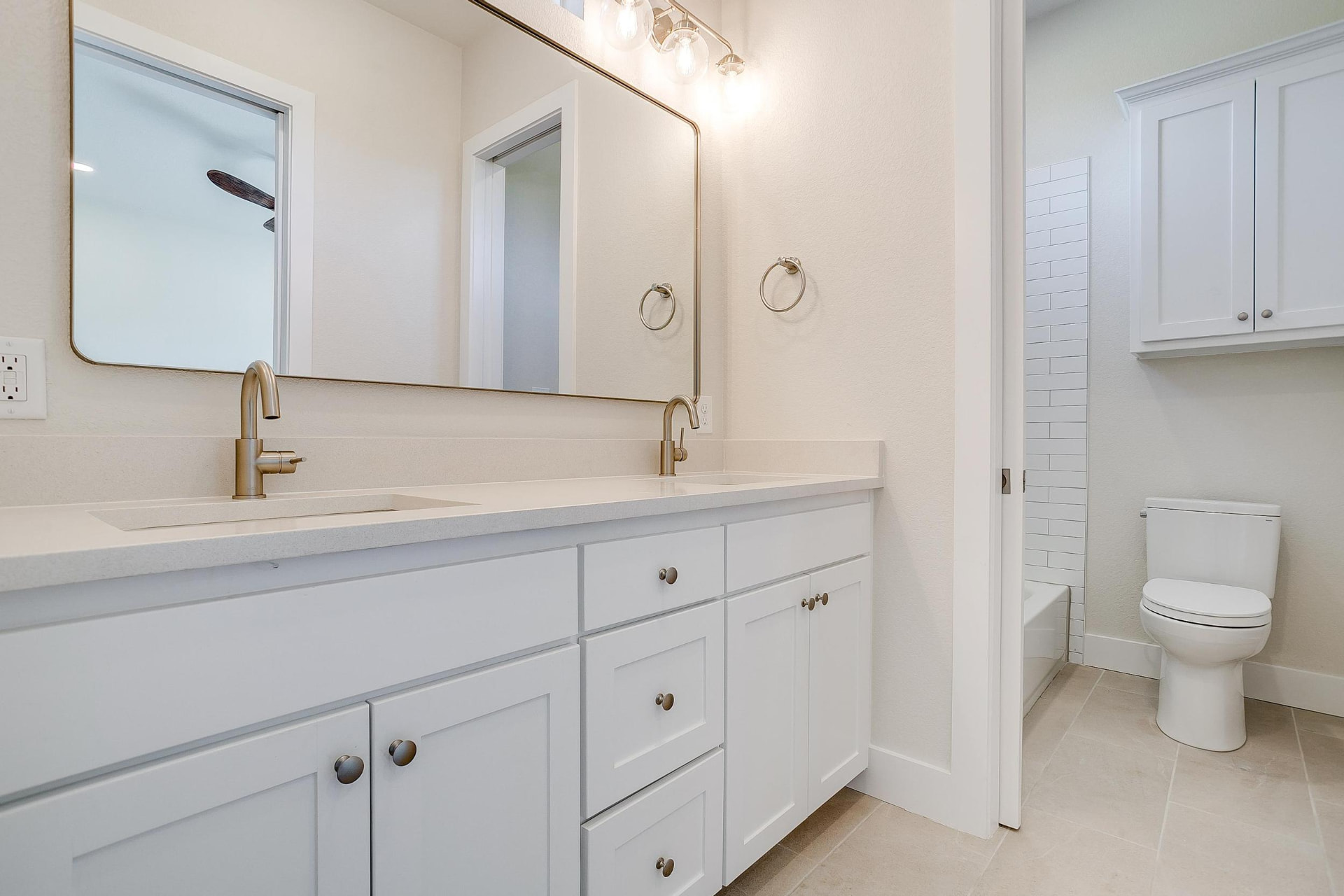Guest bathroom with a white double vanity and gold faucets