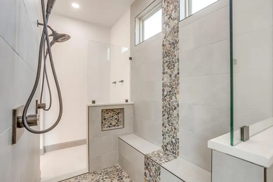 Walk-in shower with glass panel, bench seat, and tiled niche