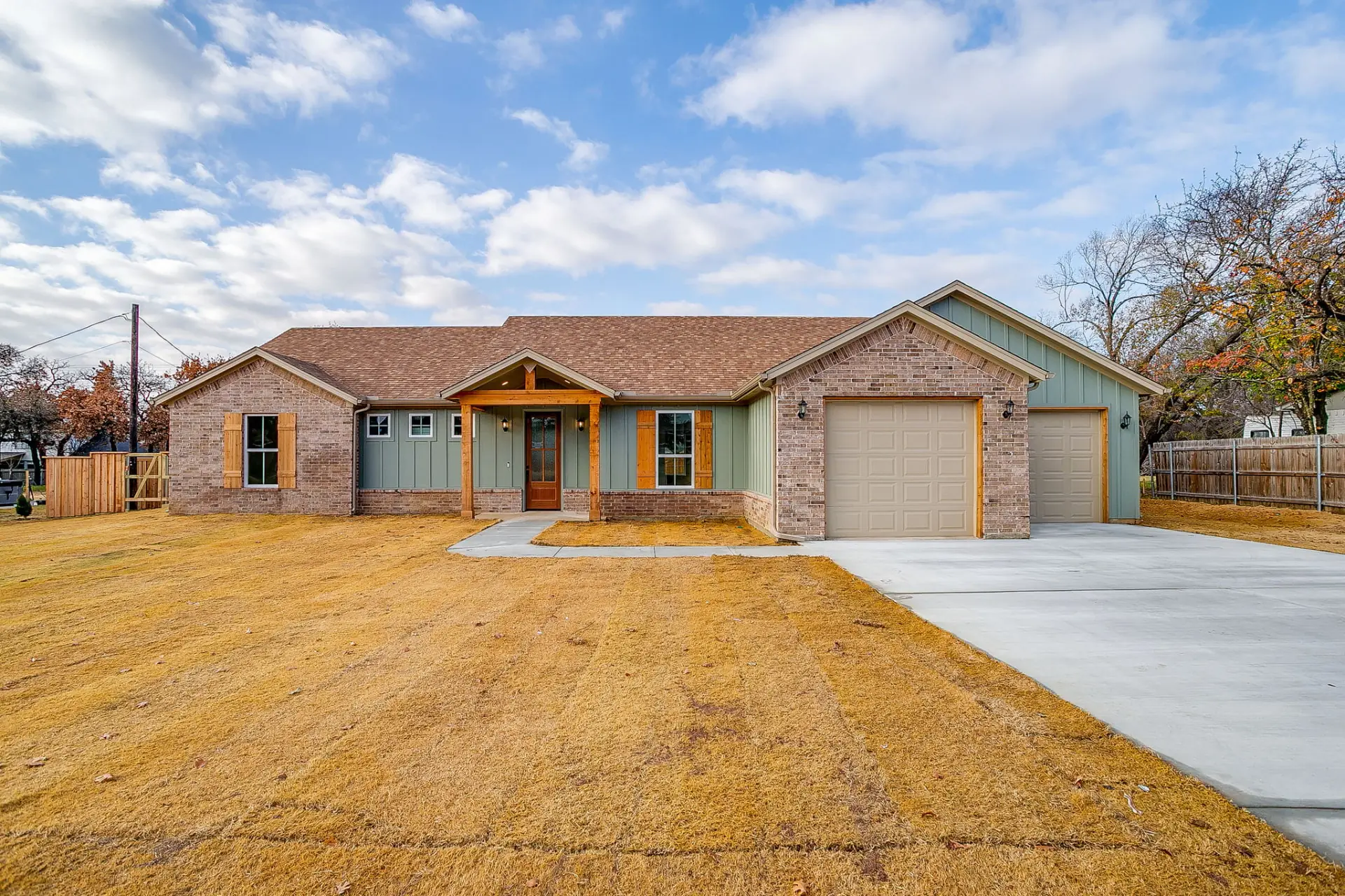 Front exterior of 436 Wicker Way, a modern ranch-style custom home in Burleson, TX with brick and green board-and-batten siding