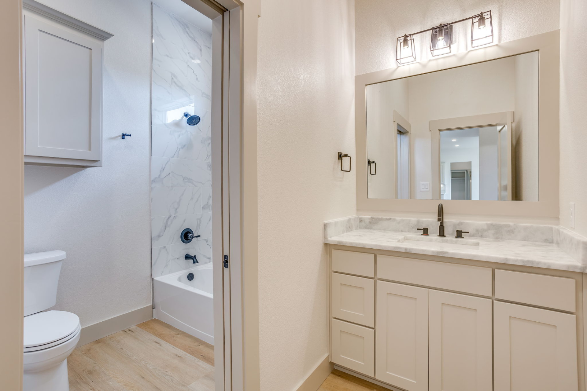 Guest bath with a marble tub-shower and separate vanity