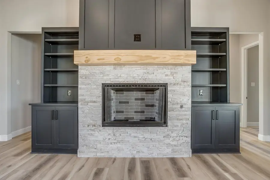 Stone fireplace with wood mantel and dark built-in shelving