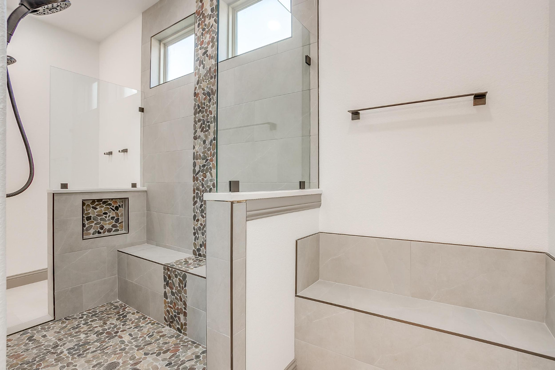 Walk-in shower with pebble floor and stone tile walls