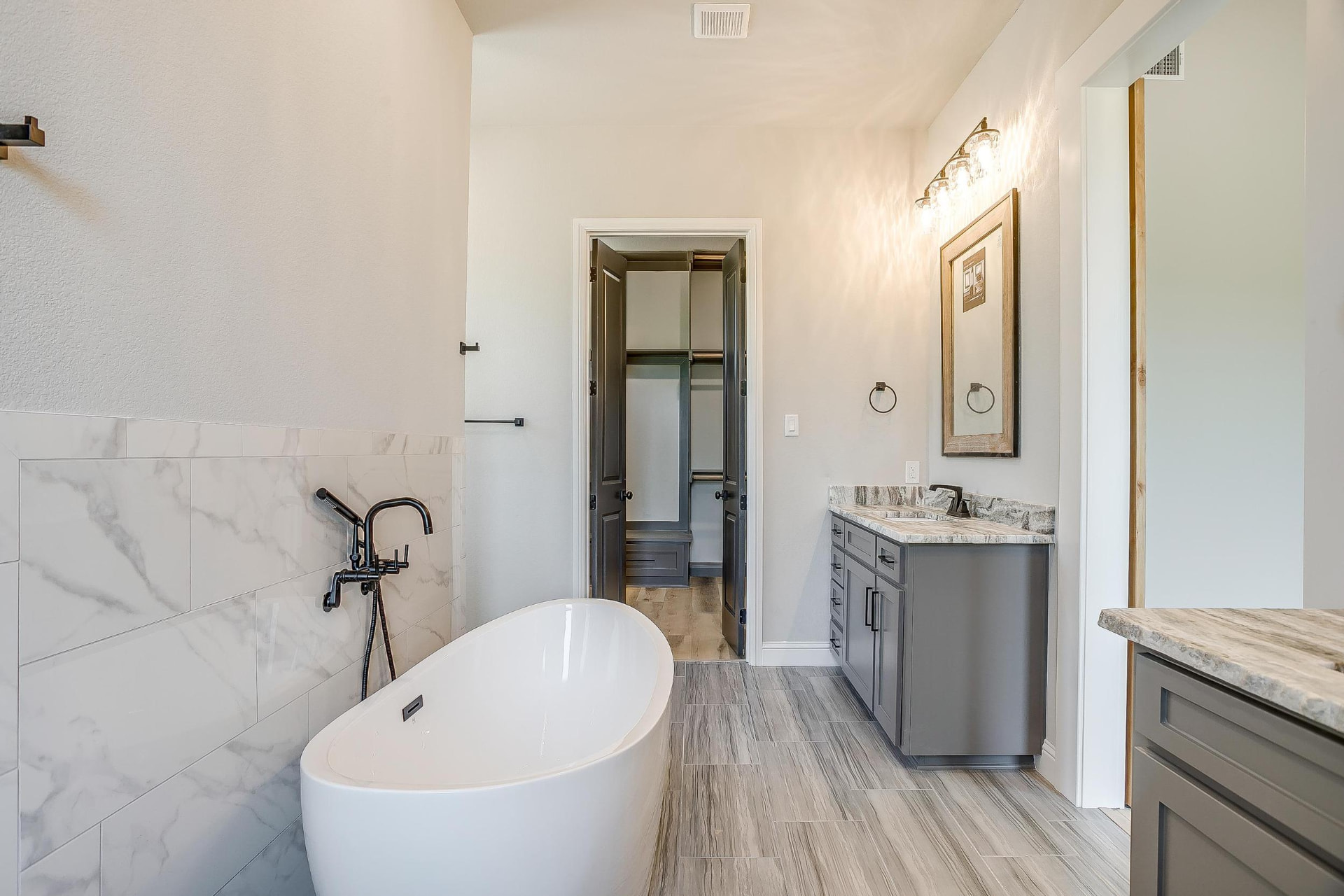 Freestanding tub against a marble tile wall in the primary bath