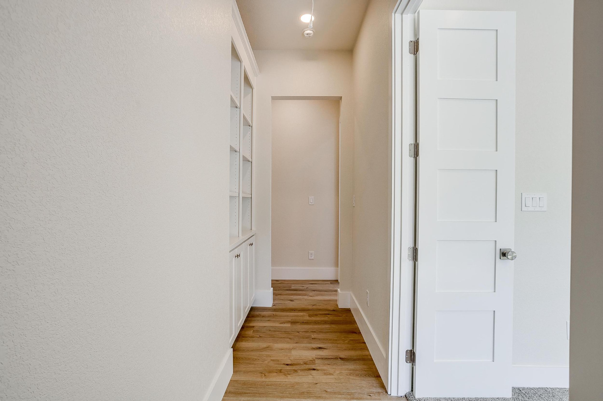 Hallway with white shaker doors and wood flooring