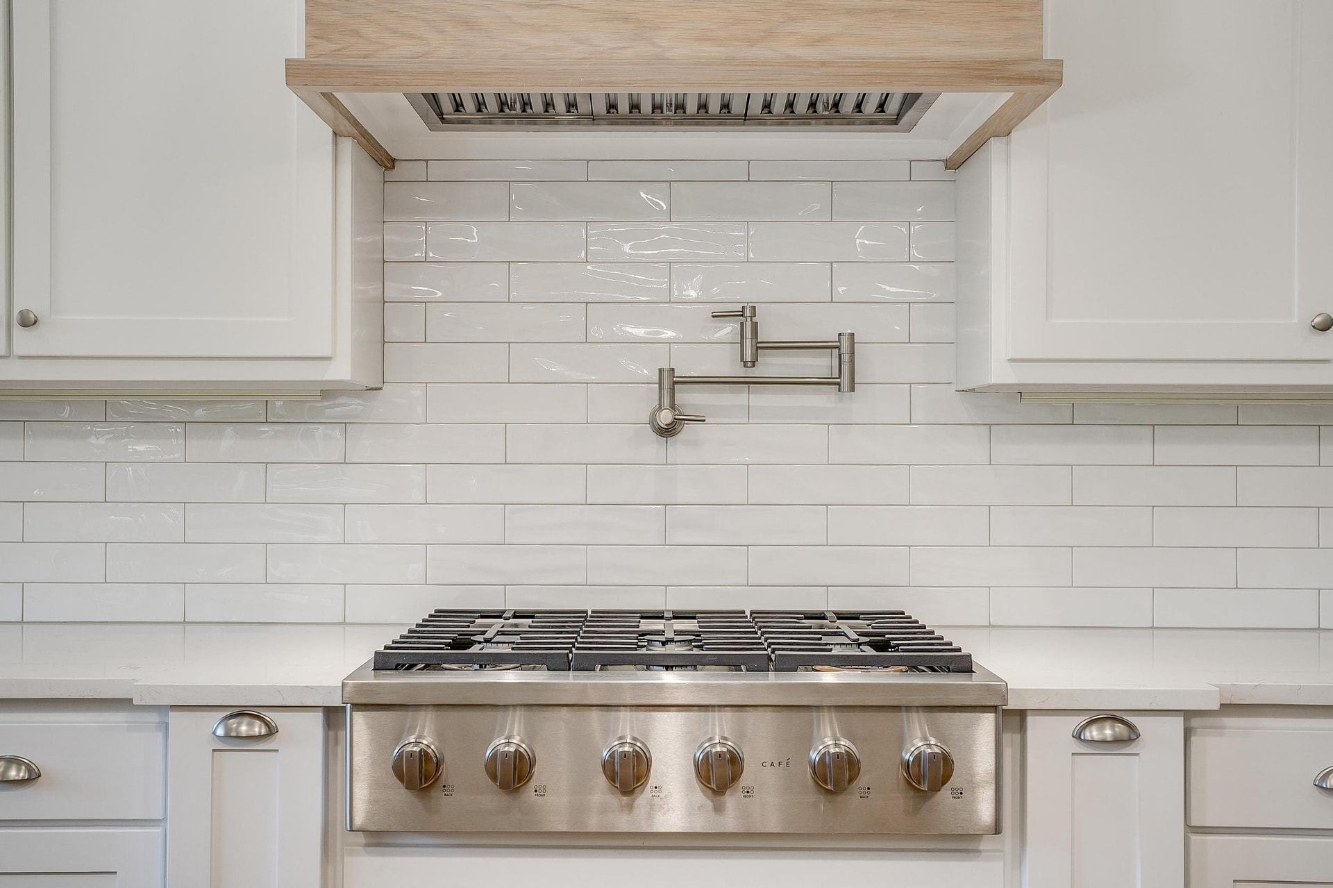 Professional gas range with subway tile backsplash and a pot filler