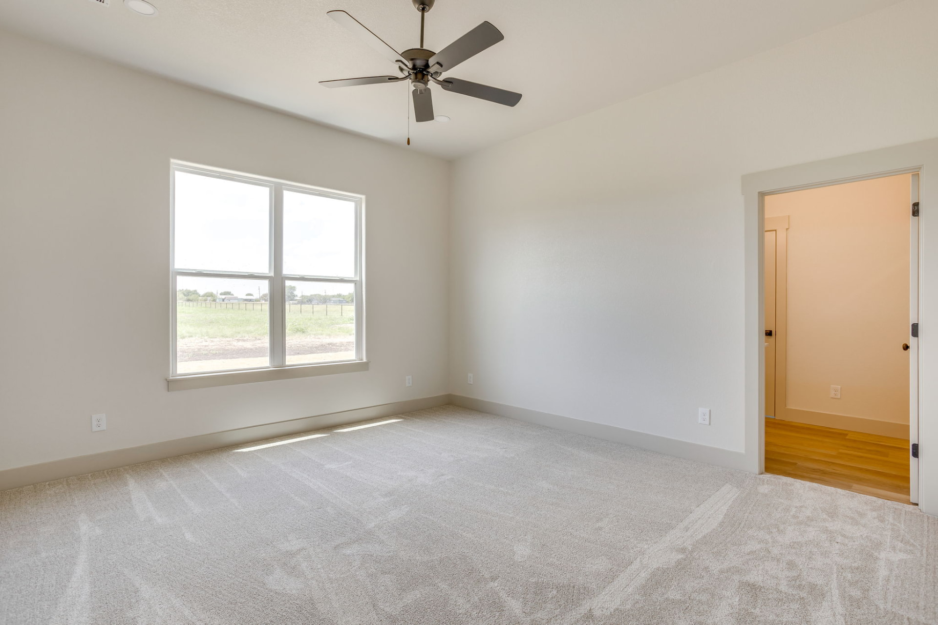 Carpeted bedroom with a ceiling fan and pasture views