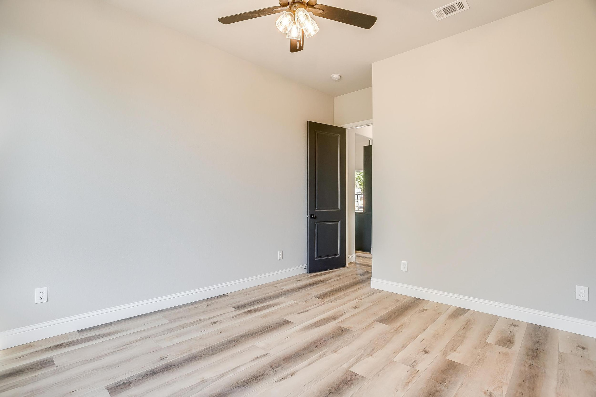 Bedroom with dark gray door and wide-plank flooring
