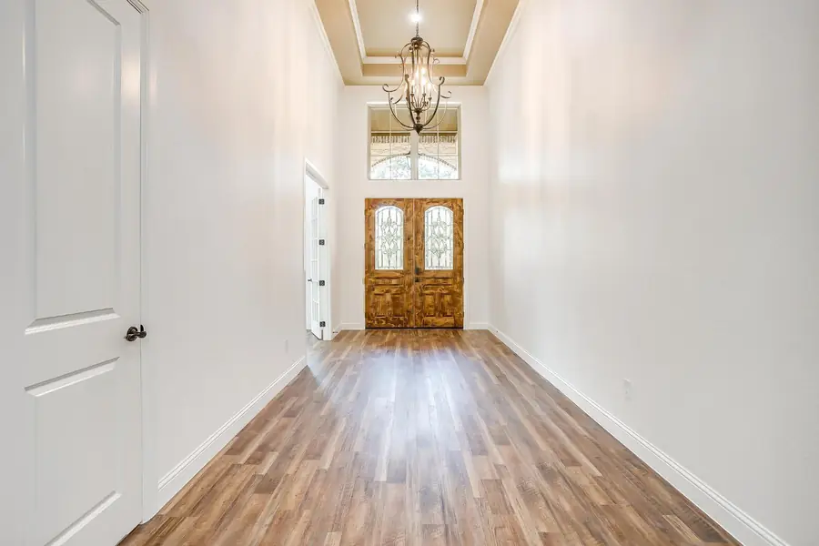 Two-story entry foyer with dark wood flooring and a view into the living room