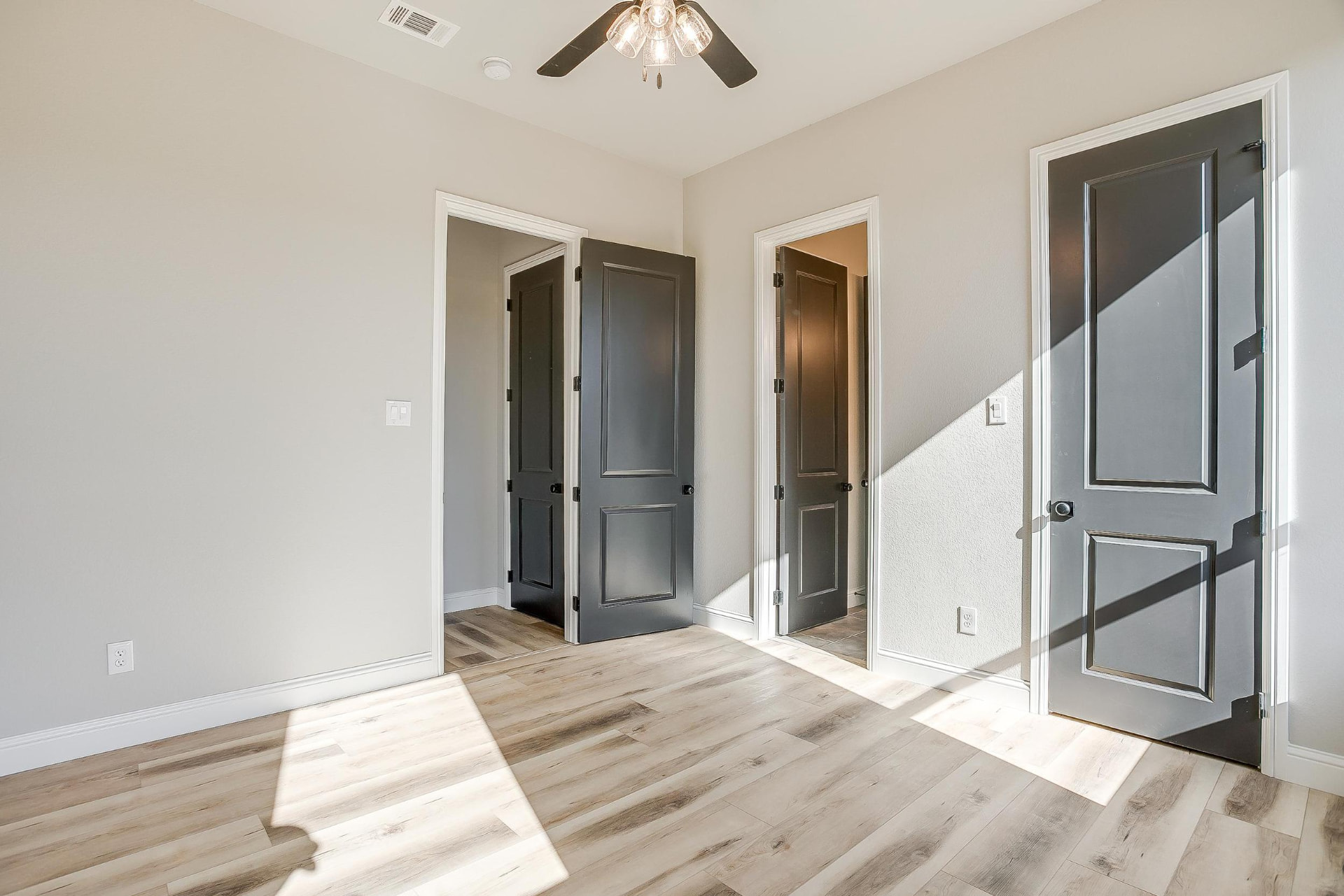 Bedroom with dark gray doors and afternoon light across the floor