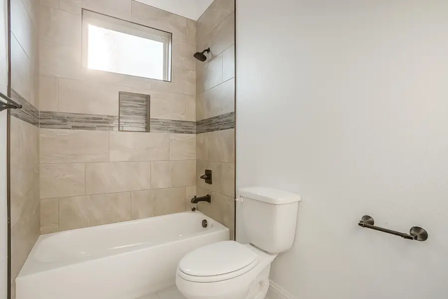 Bathroom with tiled tub-shower combination and dark hardware
