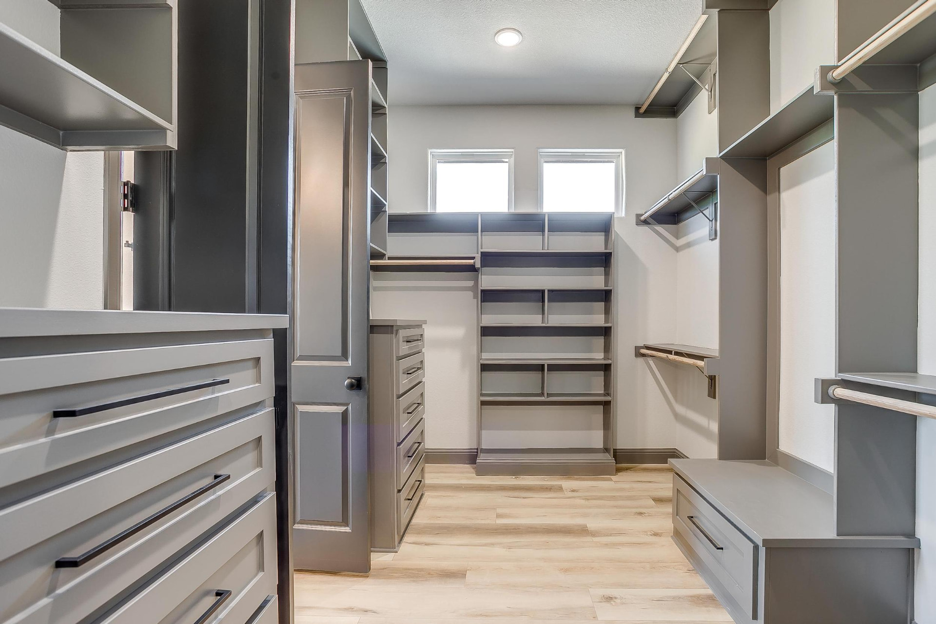 Large primary walk-in closet with built-in shelving and drawers