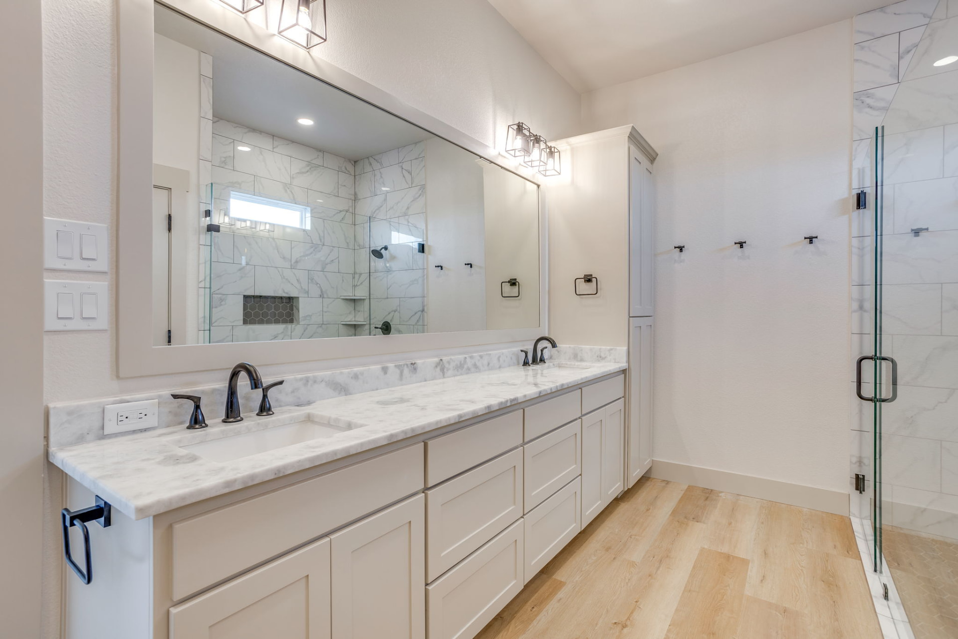 Primary vanity with marble counters and black faucets