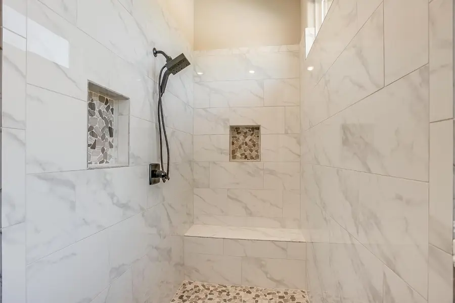 Marble tile walk-in shower with pebble niches and bench