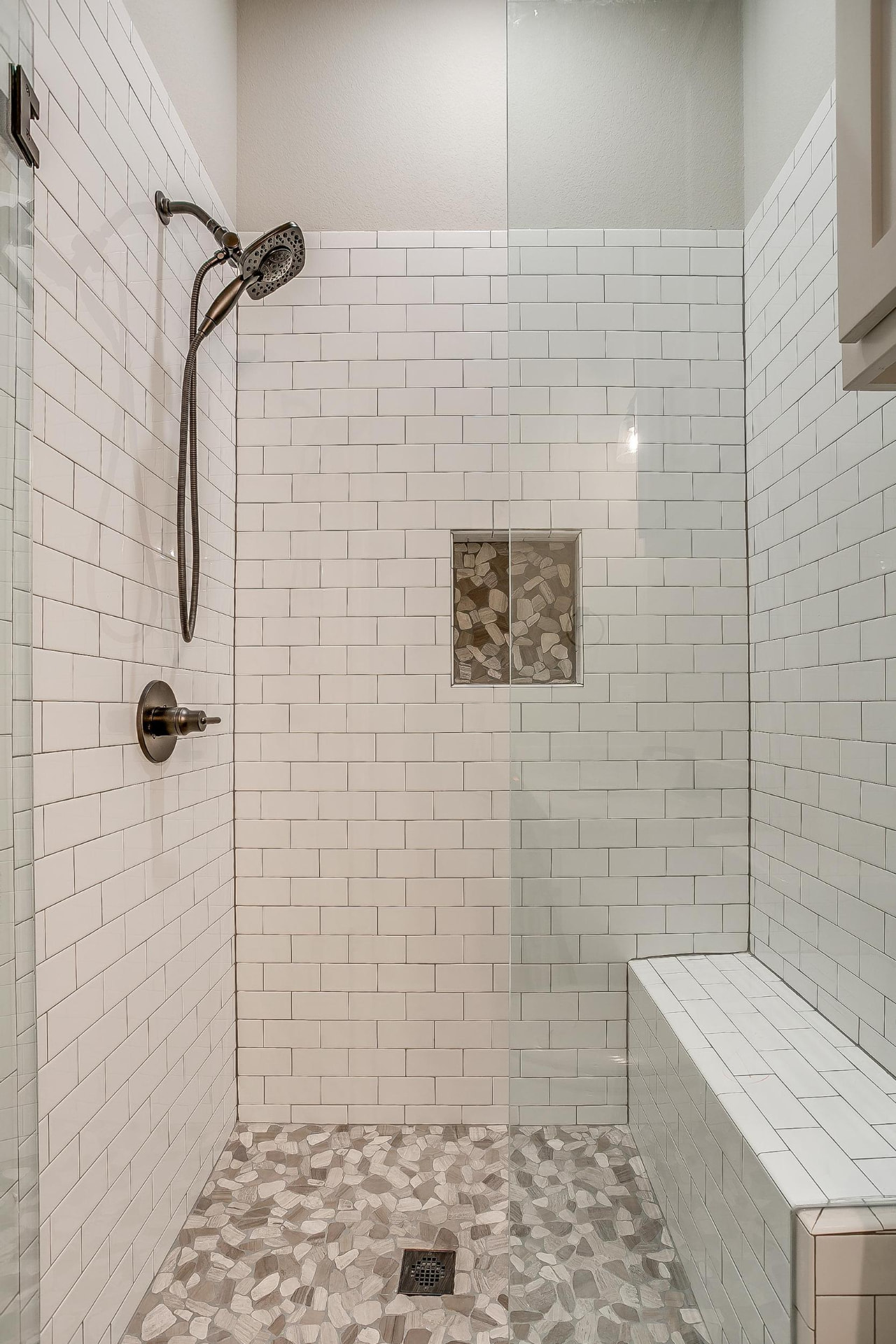 Shower interior with pebble tile floor and built-in bench