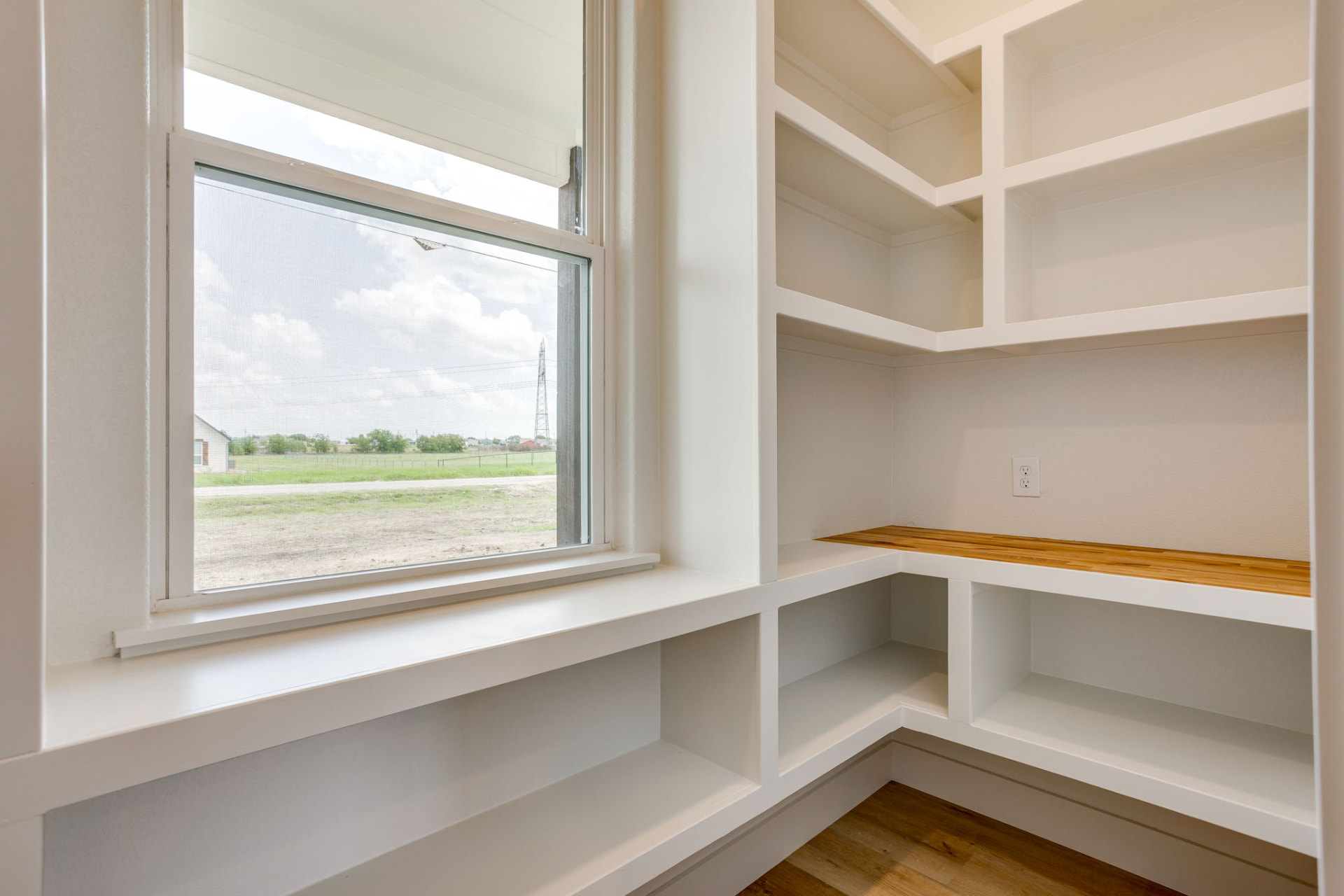 Walk-in pantry with white shelving and a window