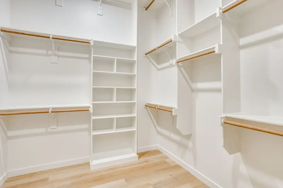 Walk-in primary closet with custom white built-ins