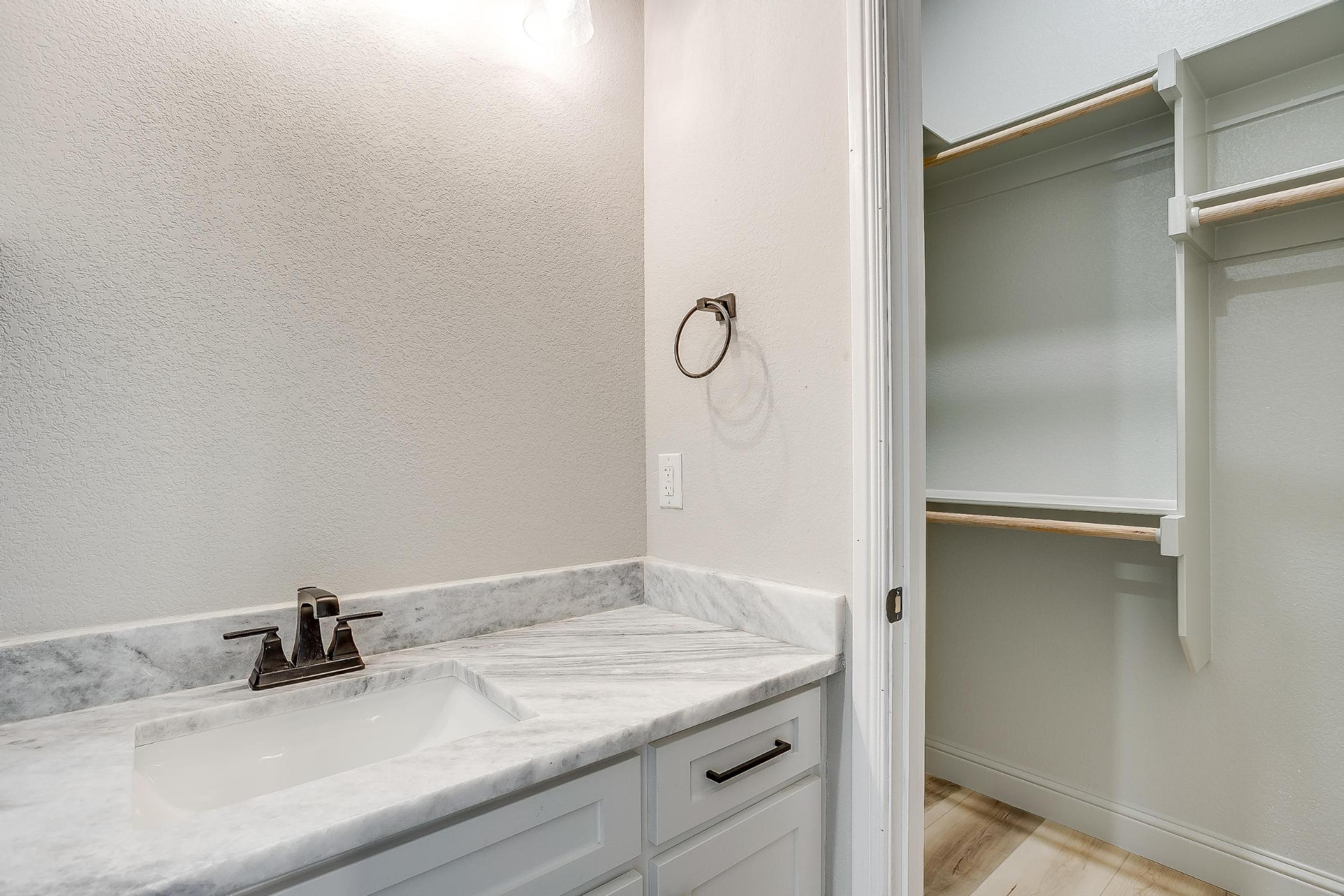 Bath vanity with marble top, matte black fixtures, and walk-in closet