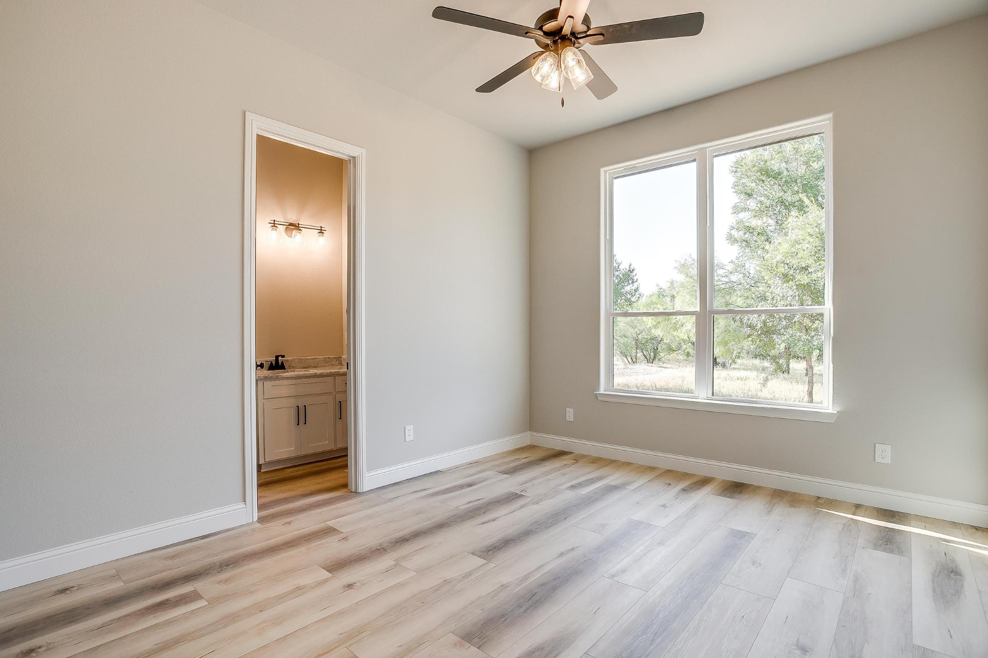 Bedroom with wood-look plank flooring leading into the ensuite bath