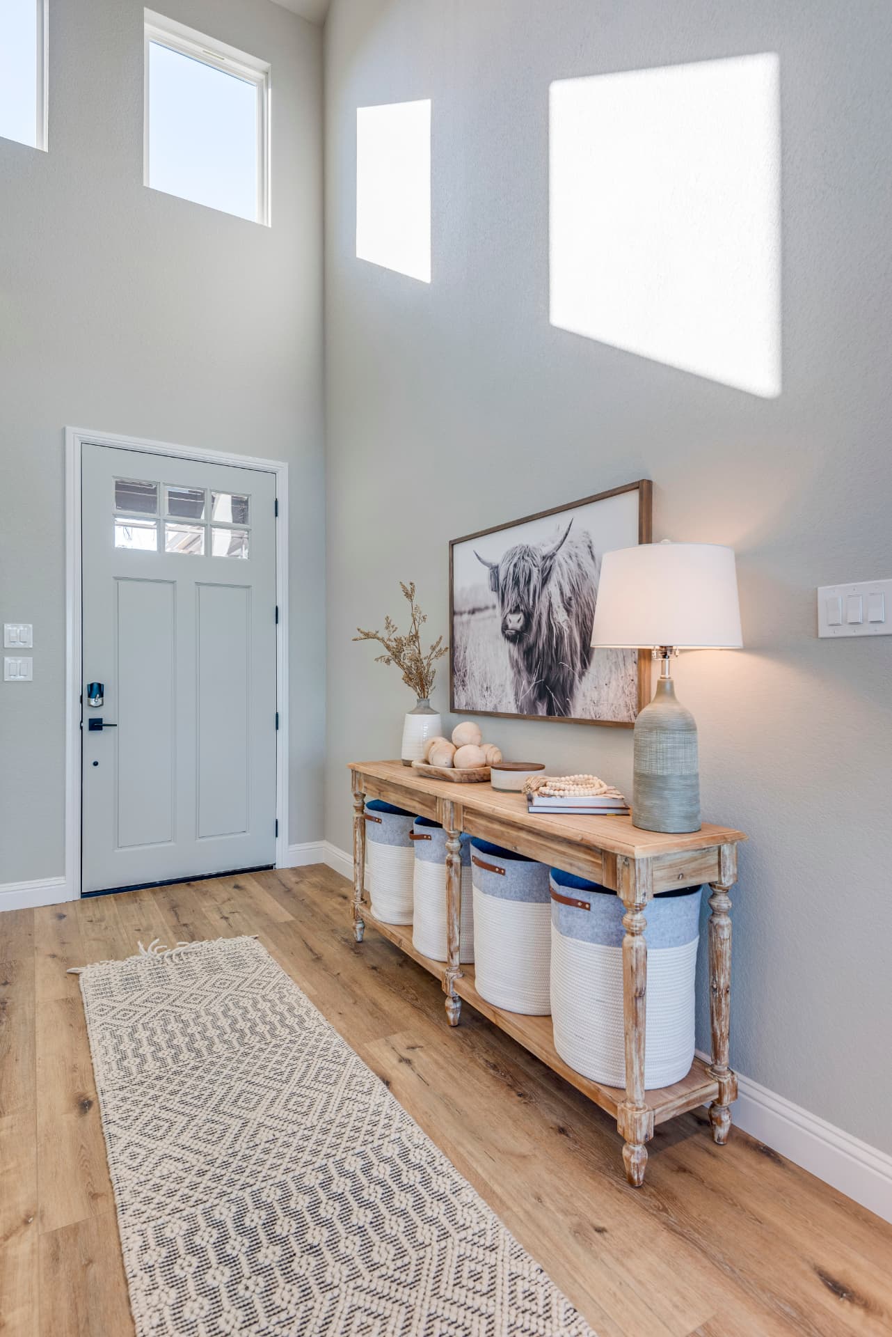 High-ceiling foyer with light wood console table and large artwork