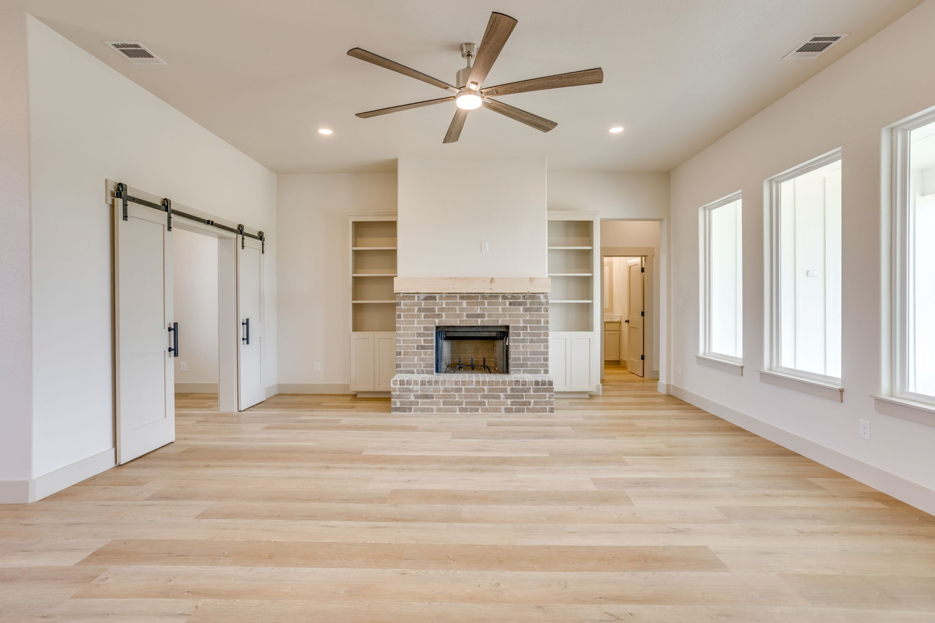 Brick fireplace flanked by white built-in shelving