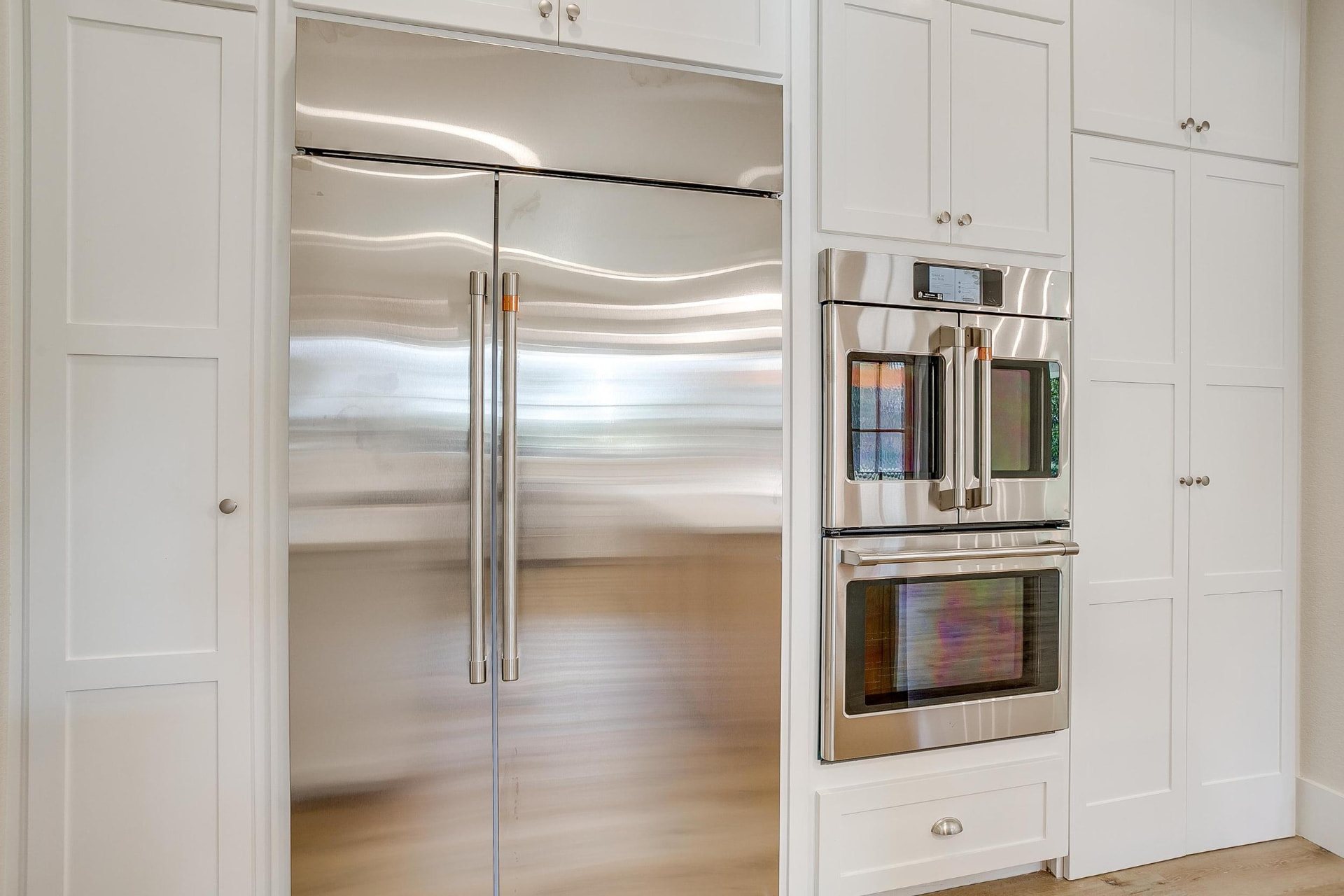 Built-in refrigerator and double wall ovens in white cabinetry