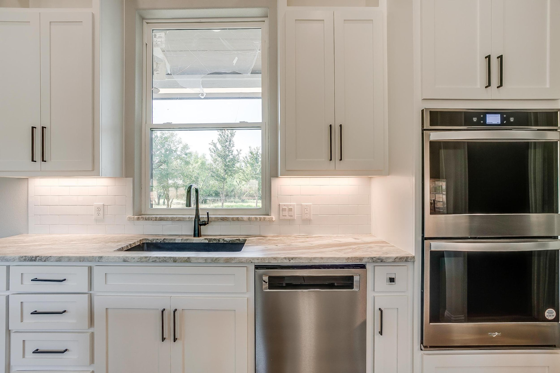 Kitchen window, farmhouse sink, and stainless wall ovens