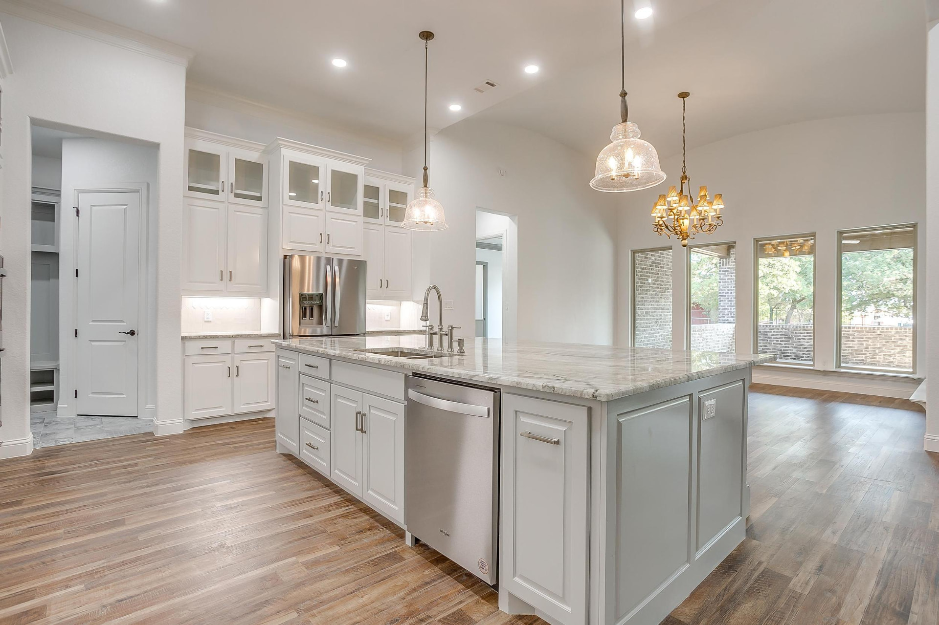 White kitchen with a marble island and glass pendant lights