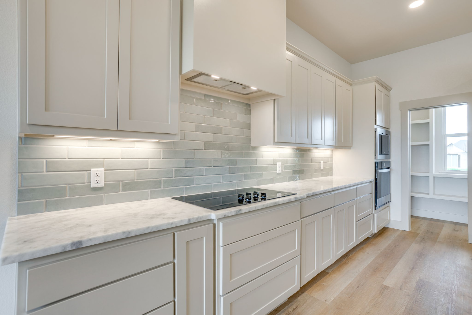 Kitchen stovetop with gray subway tile backsplash