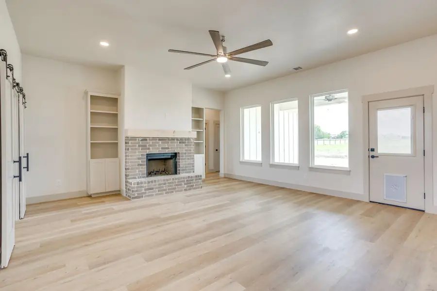 Living room with a brick fireplace, wood mantel, and tall windows