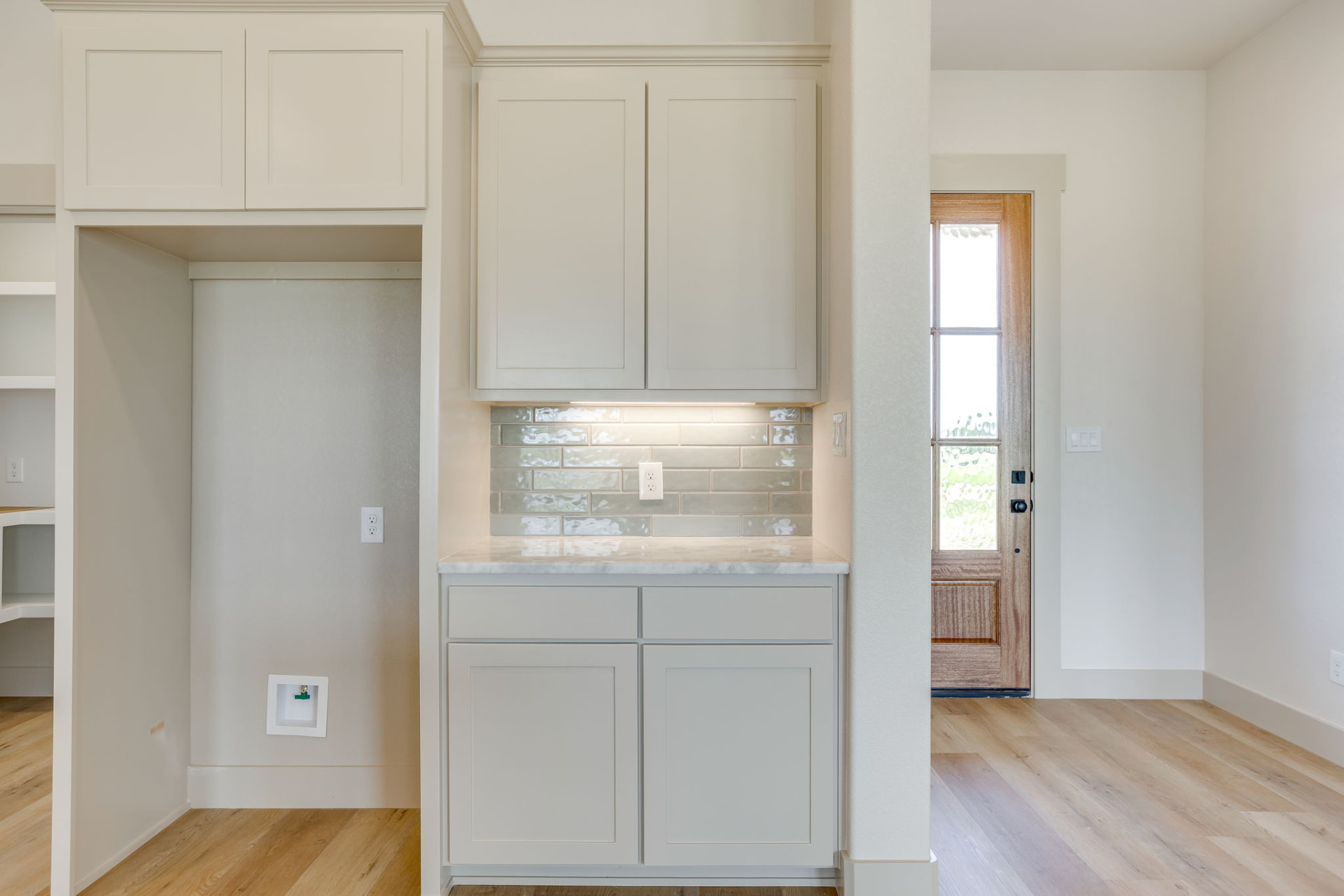 Built-in kitchen cabinetry with light gray tile backsplash