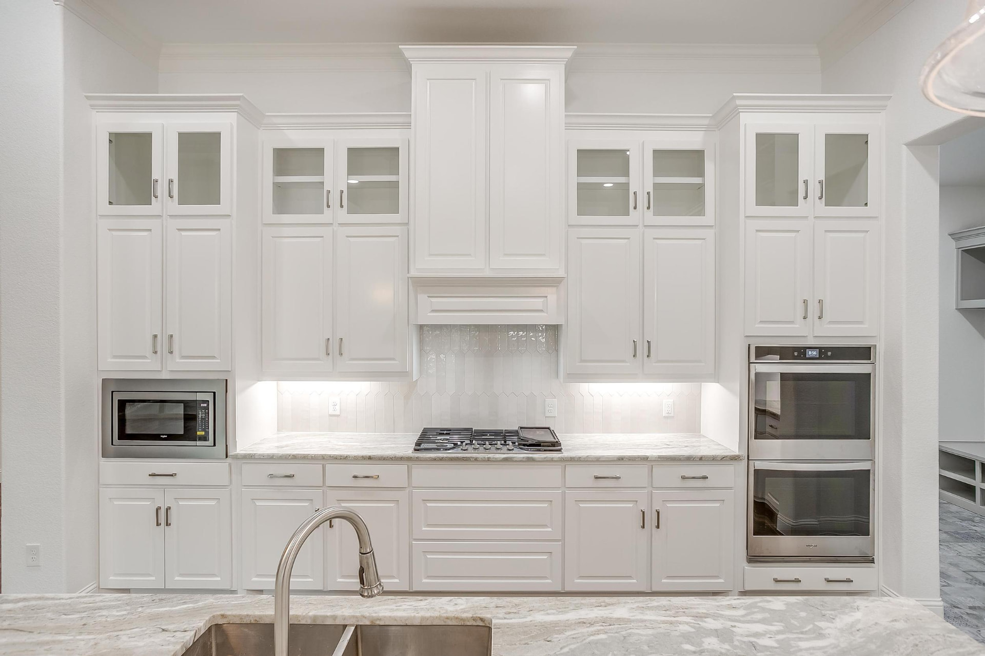 Symmetrical view of white kitchen cabinetry and range wall