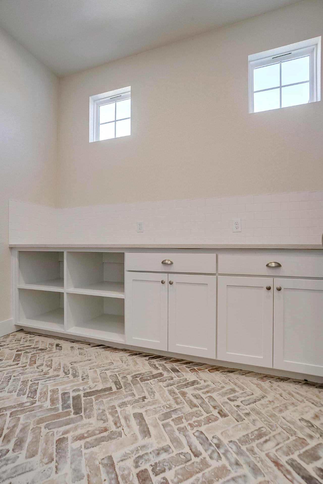 Laundry cubbies and cabinetry over brick herringbone floors