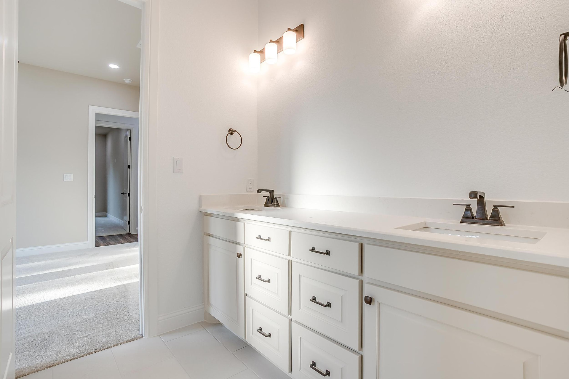 White double vanity with stone counters and bronze faucets