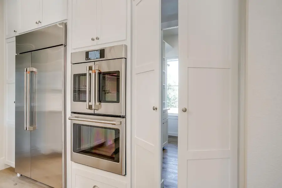 White pantry doors beside the built-in ovens