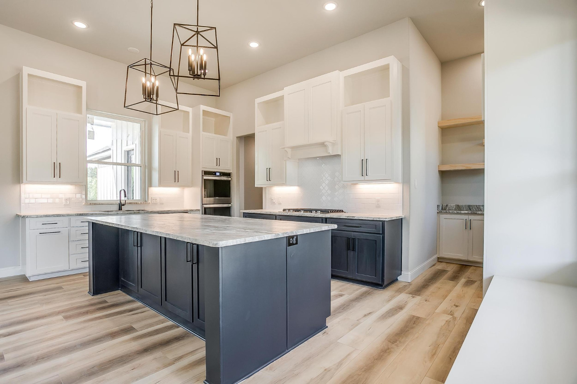 Contemporary kitchen with white cabinetry and a navy island