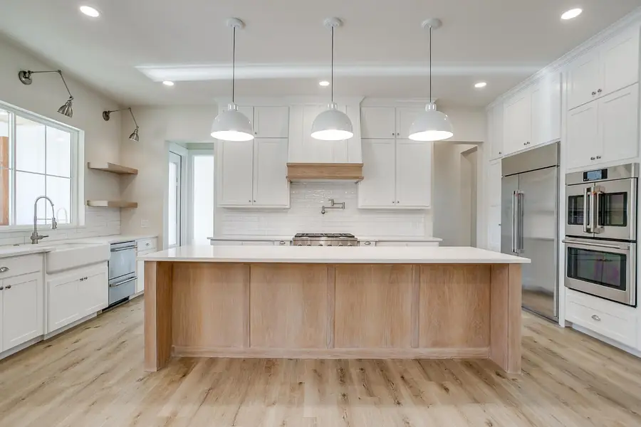 Kitchen with a large marble-topped wood island and white cabinetry