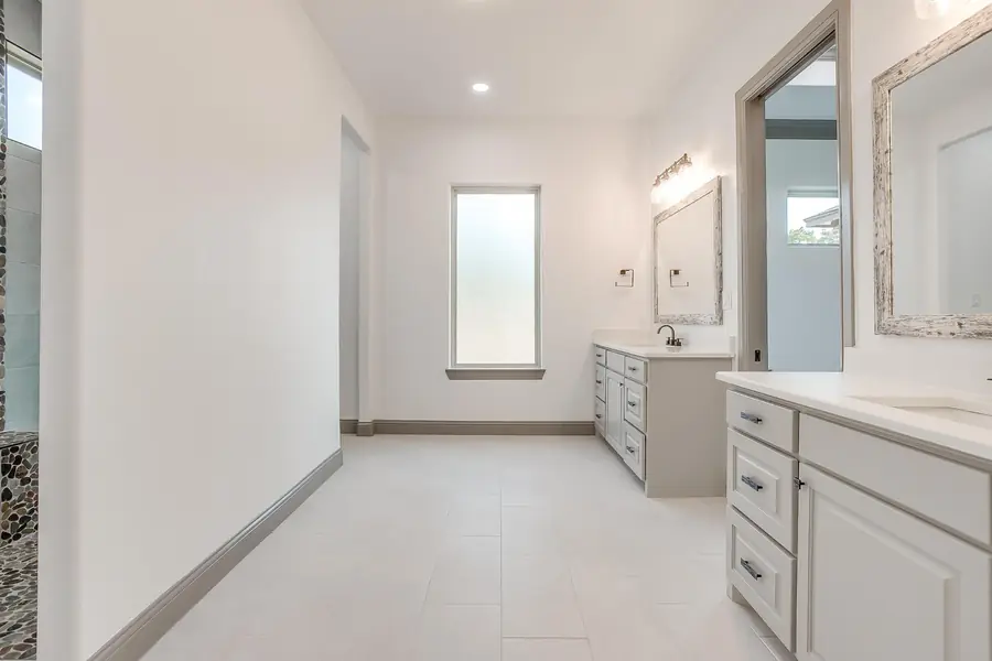 Primary bathroom with light tile flooring and dual vanities