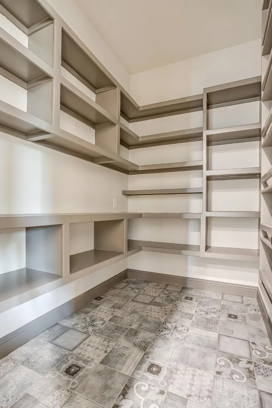 Walk-in pantry with gray shelving and patterned floor tile