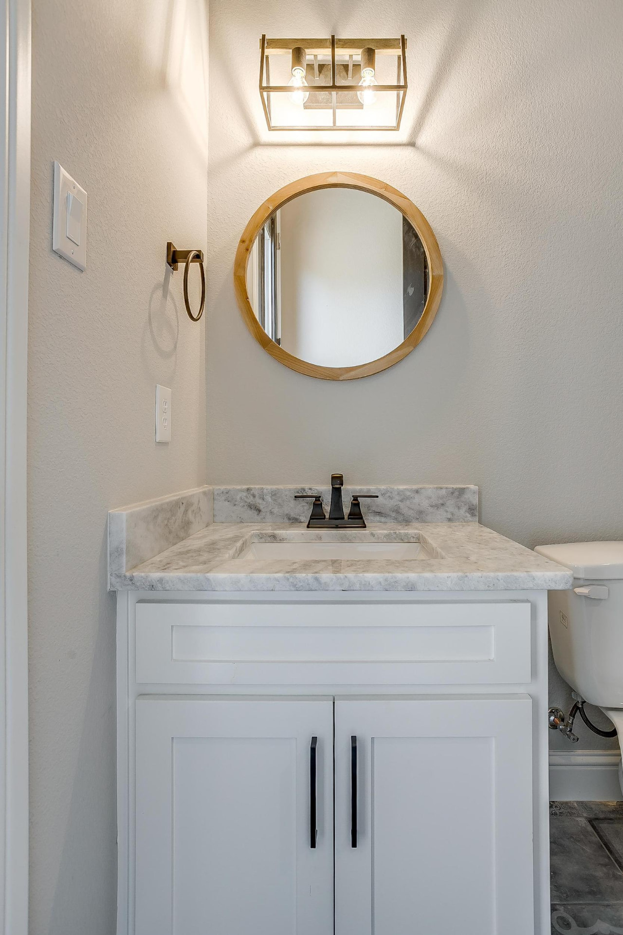 Powder room vanity with round wood-framed mirror