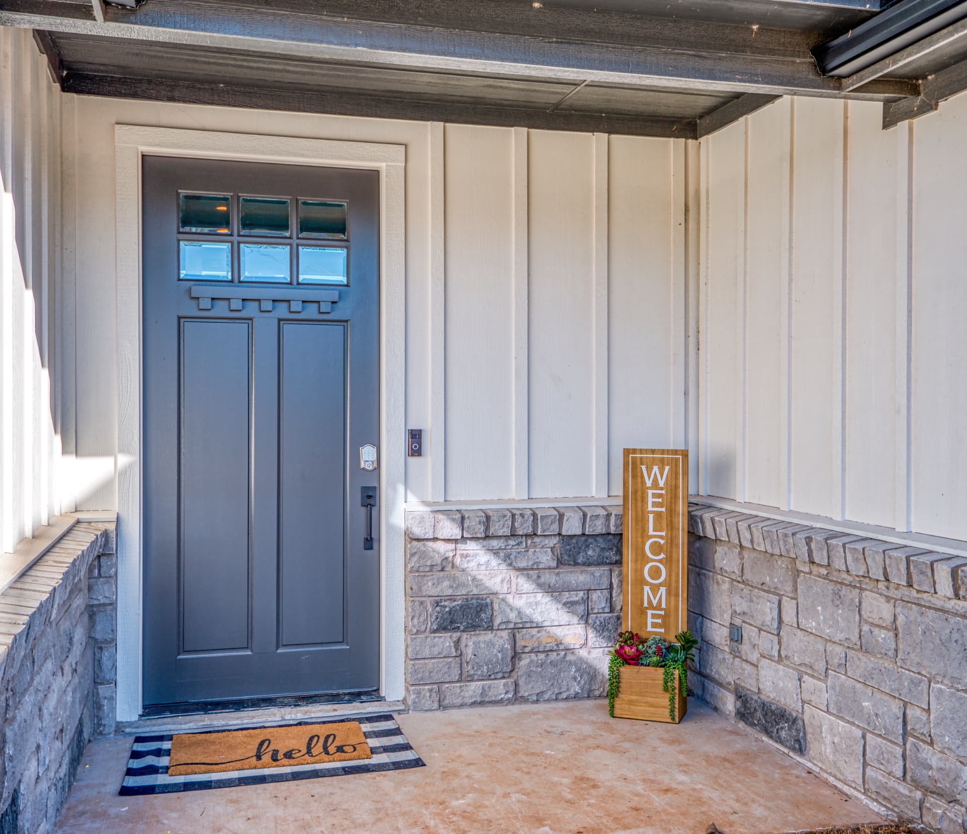Dark gray front door with welcome sign and doormat