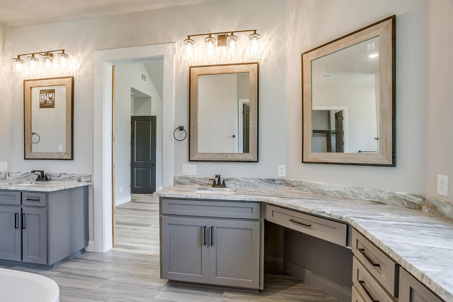 Primary bath with dual gray vanities, marble counters, and framed mirrors