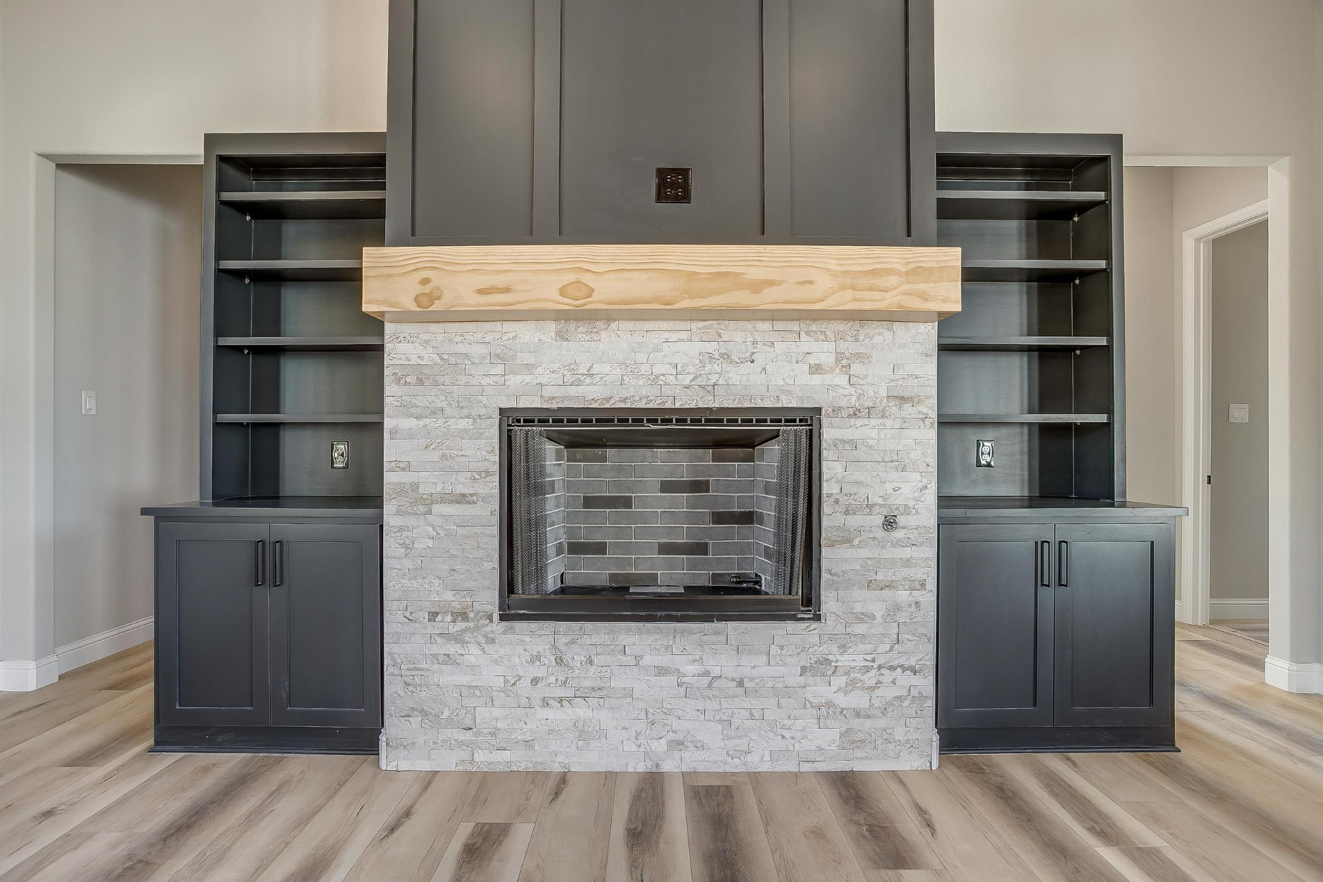 Stone fireplace with wood mantel and dark built-in shelving