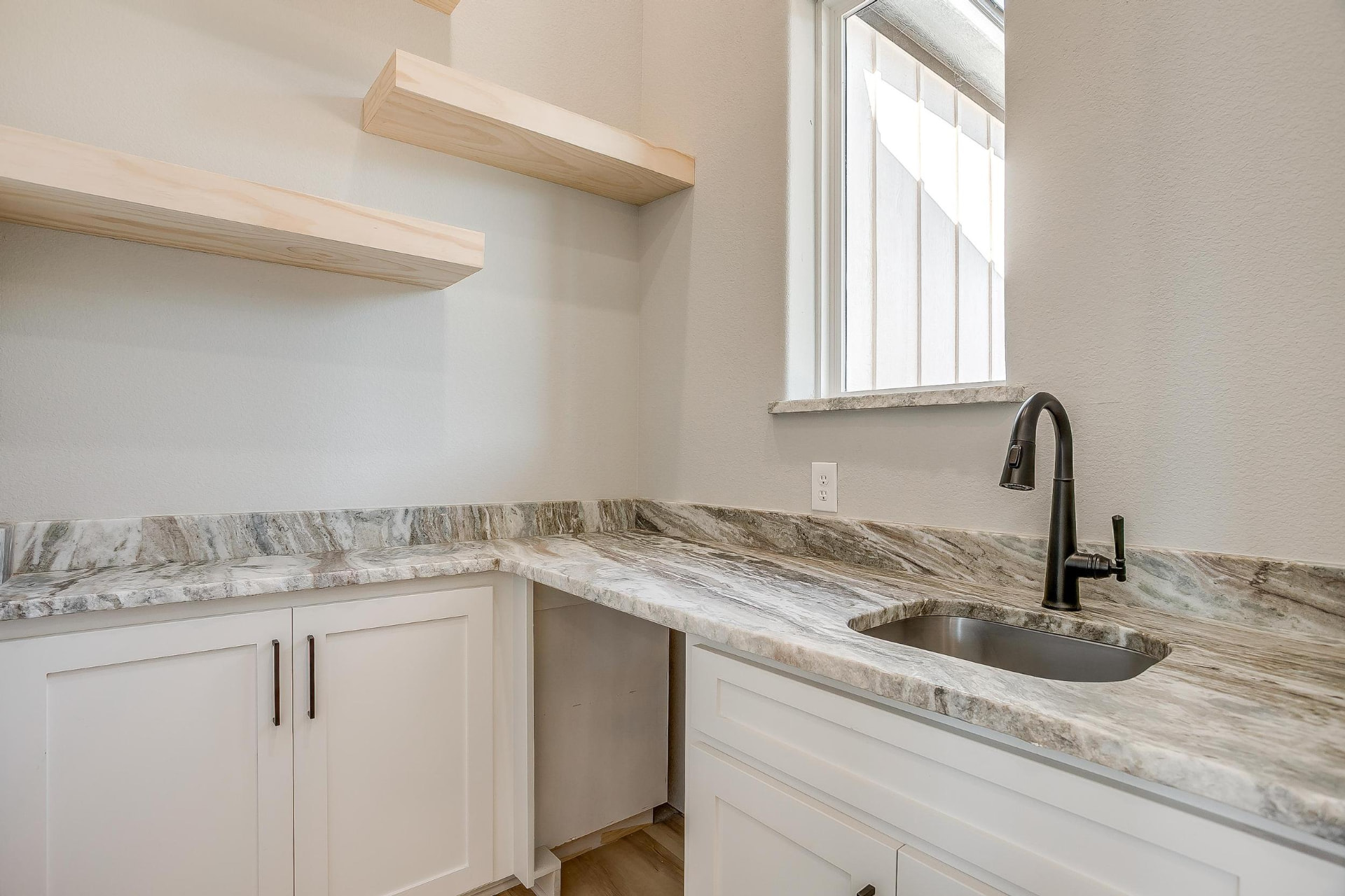 Prep and laundry room with marble counters and floating wood shelves