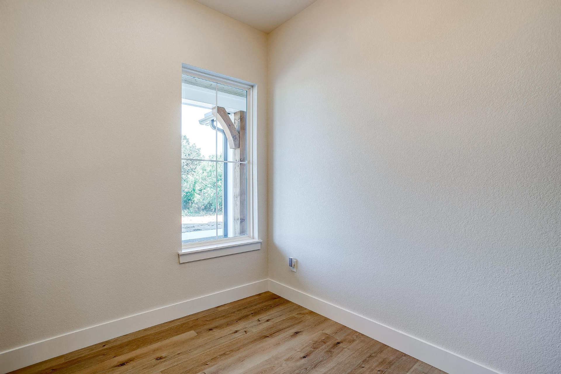 Corner of the office with a tall window and cedar porch post beyond