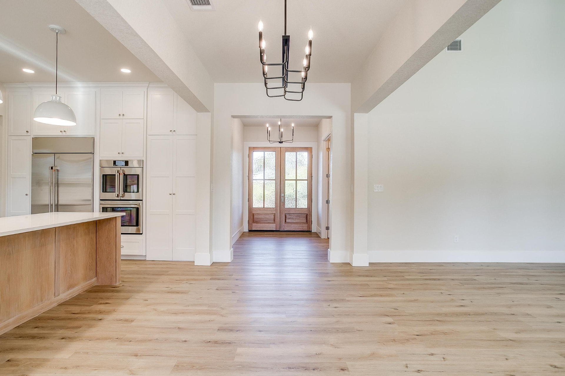 Foyer looking toward the wood front doors with the kitchen island at left