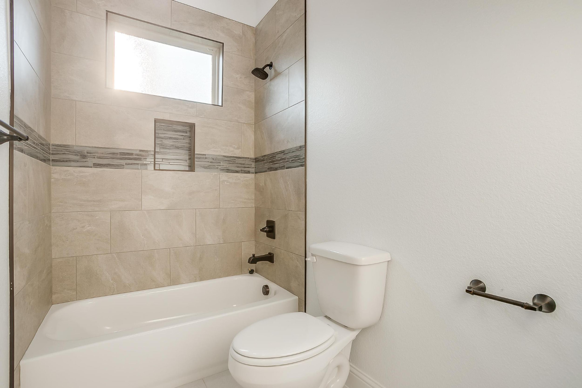 Bathroom with tiled tub-shower combination and dark hardware