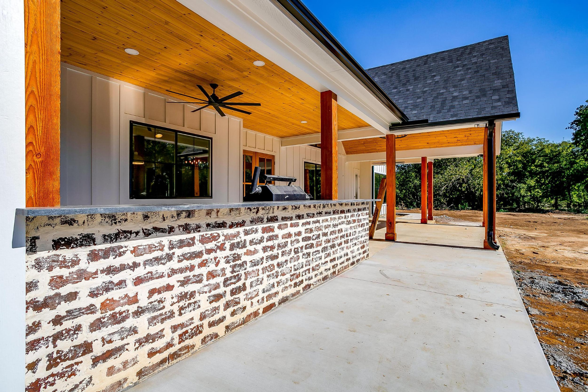 Covered back porch with cedar posts, a brick bar, and a wood ceiling